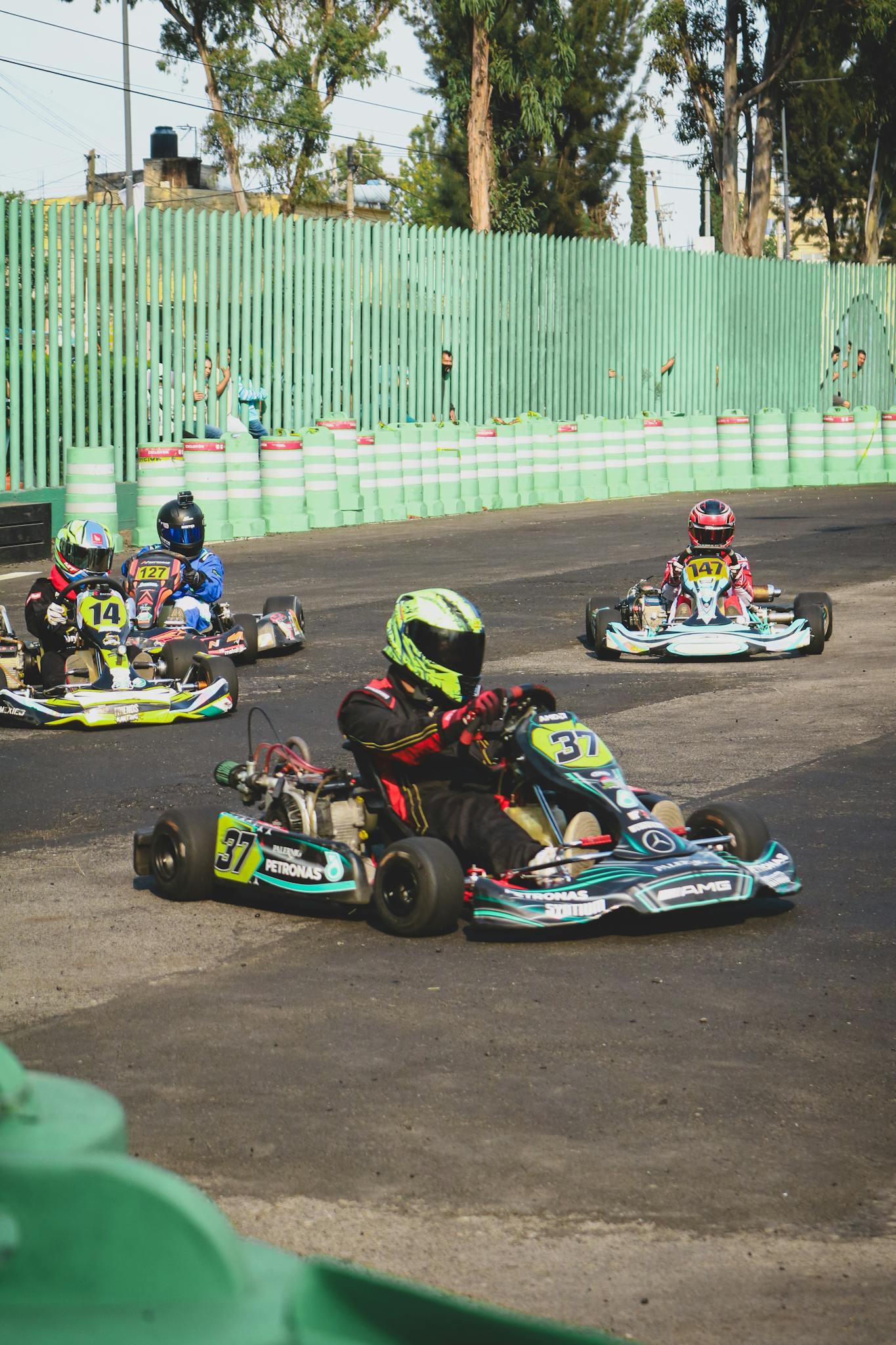 Exciting go-kart race with drivers competing on an asphalt track outdoors.
