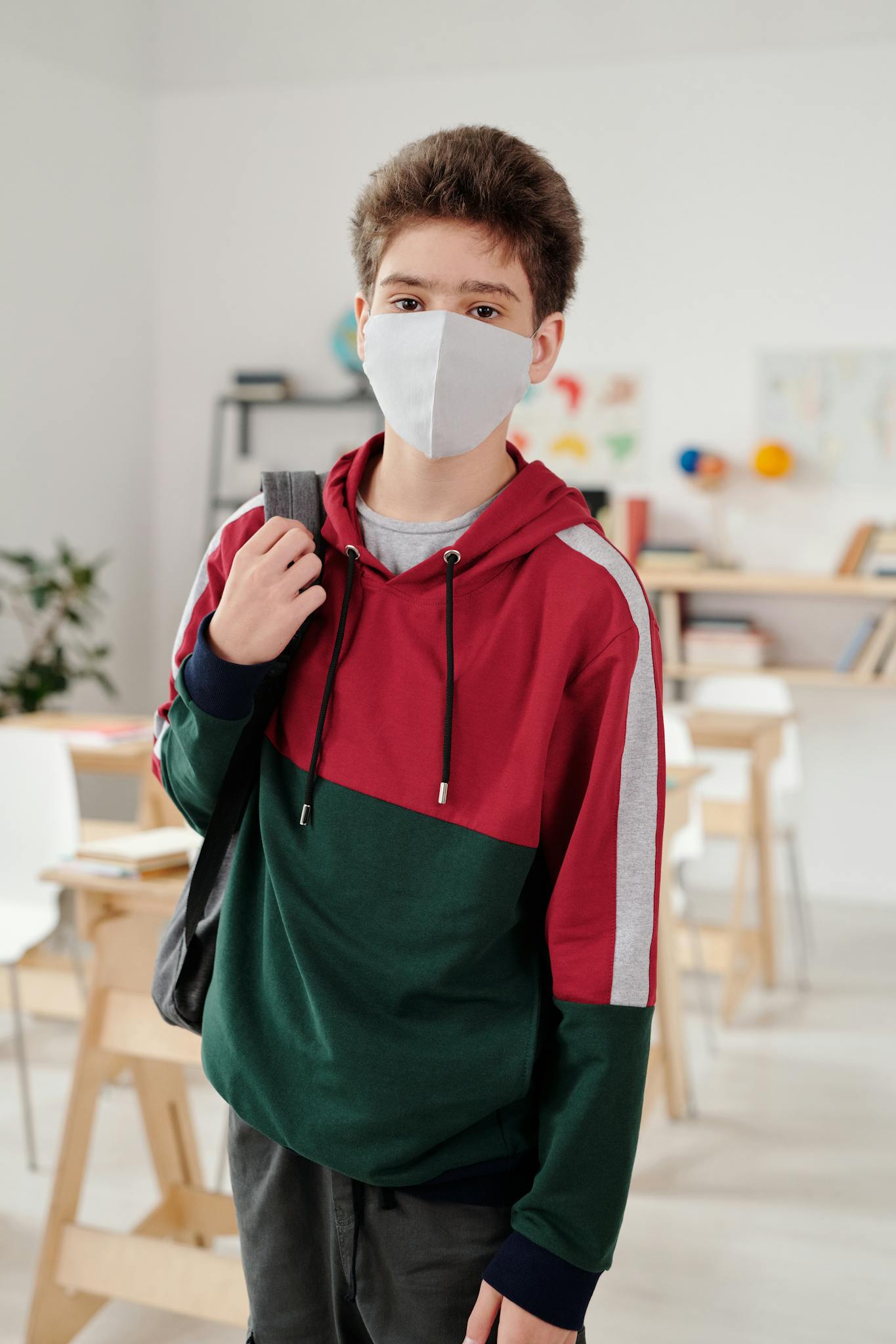 Teenage student wearing a face mask in a modern classroom setting for pandemic safety.